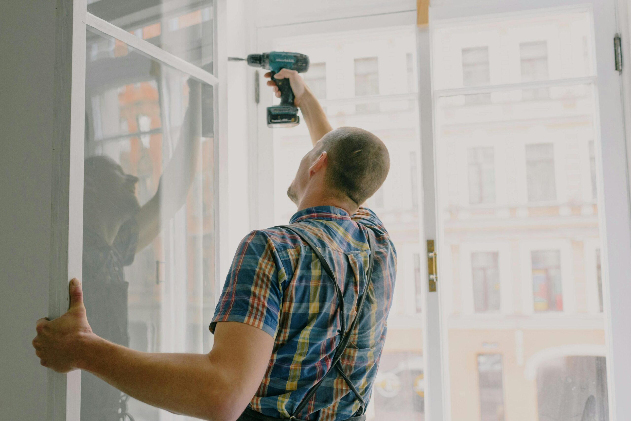Handyman technician drilling window frame during a home repair service
